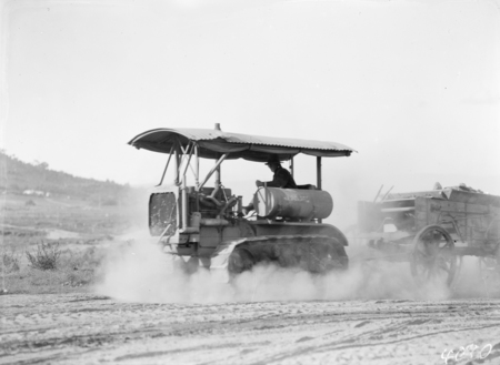 Crawler tractor towing wagon load of rocks.