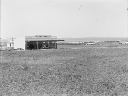 Kingston shops. Campbell's chemist shop and Hayes and Russell general store, Kennedy and Eyre Streets corner. Causeway houses in background.