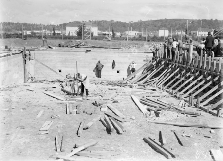 Manuka swimming pool under construction. Two walls now complete, concrete being poured on the right. Manuka Circle, Kingston.