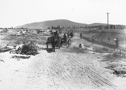 Workmen with drays preparing the foundations of Parliament House. Reinforcing steel on the left, trenches on the right